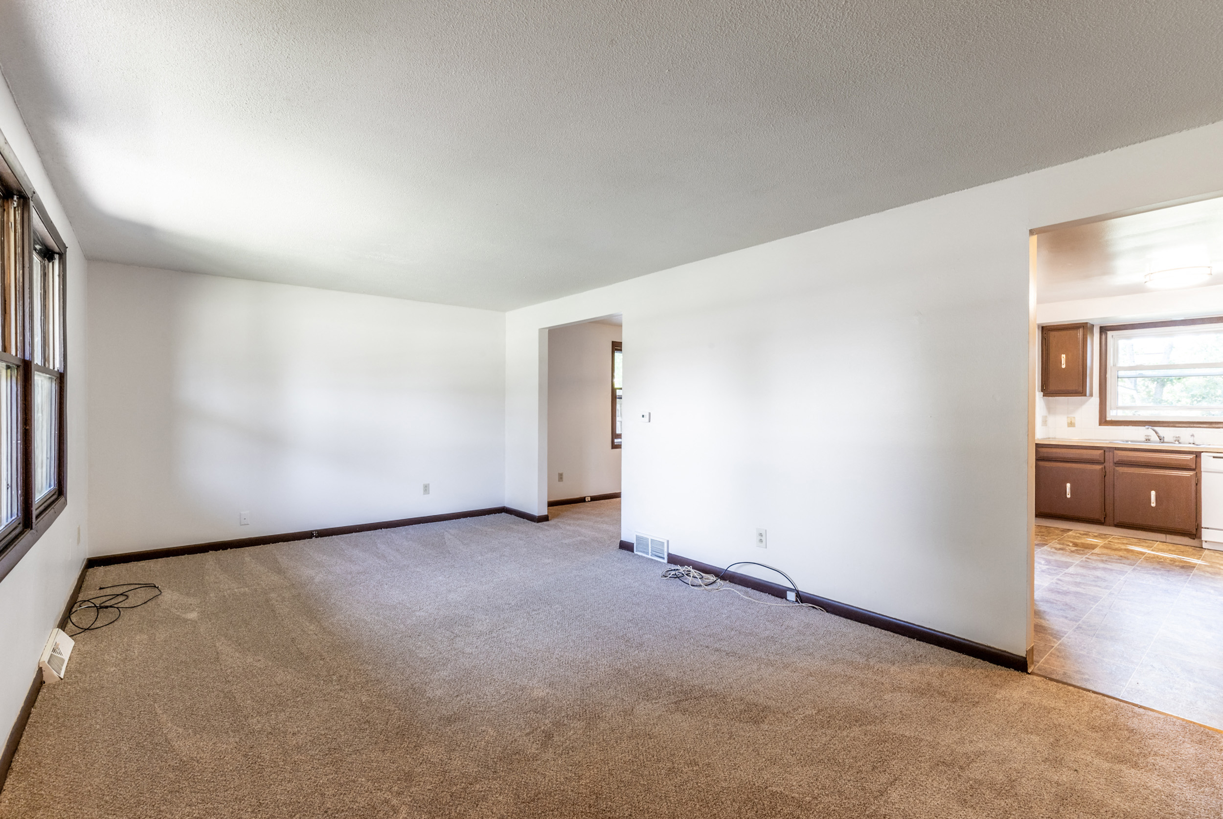 the living room and dining room of an empty house with white walls