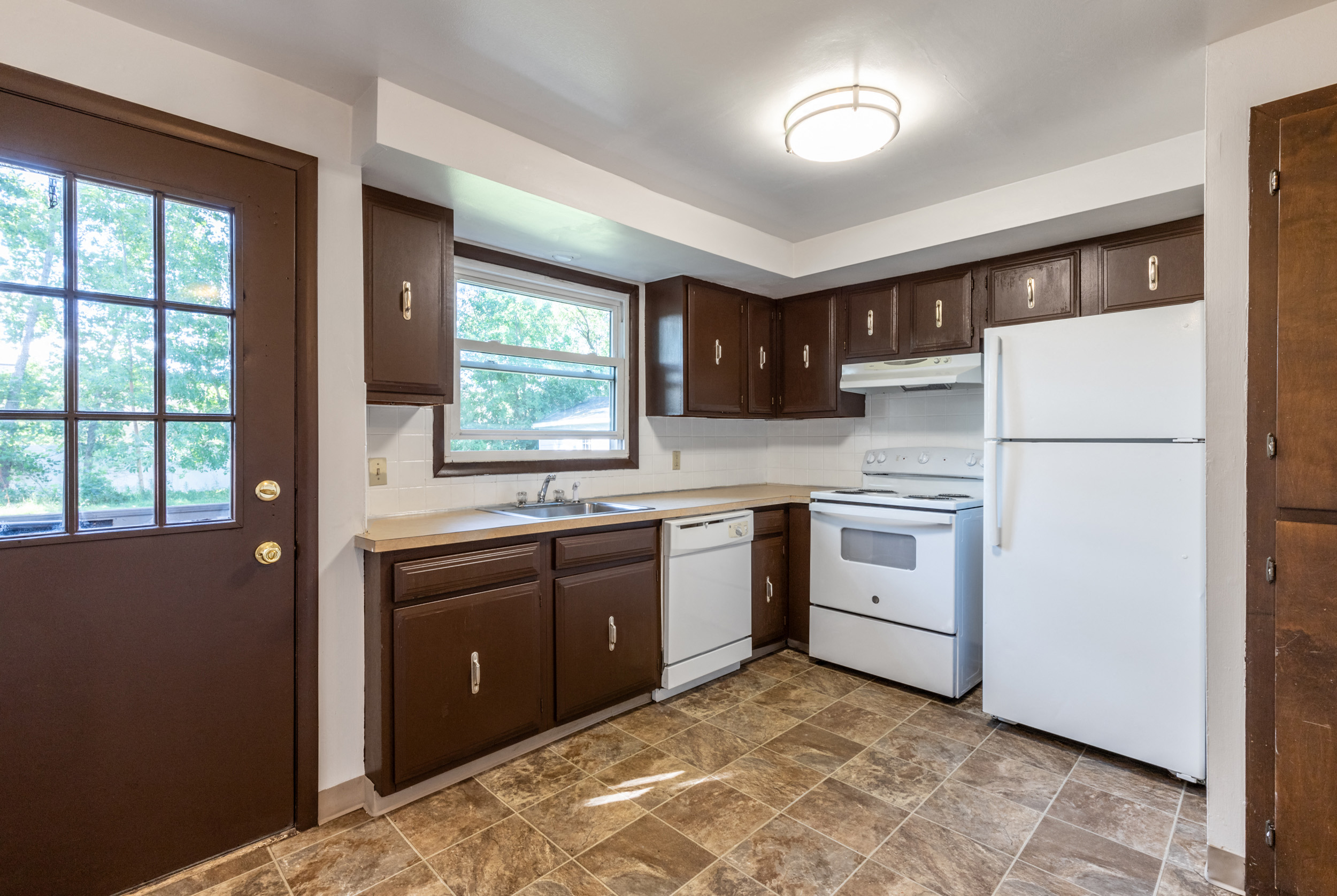 an empty kitchen with white appliances and brown cabinets
