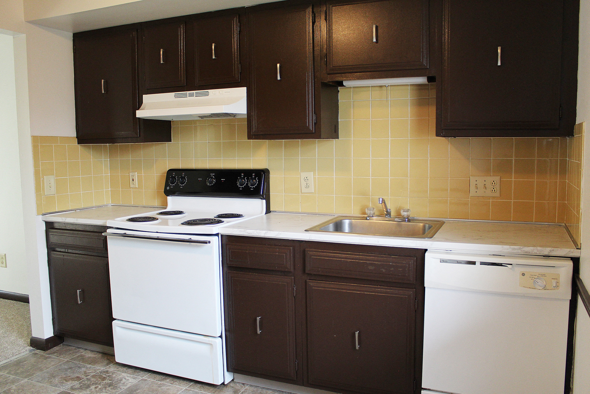 an empty kitchen with white appliances and brown cabinets