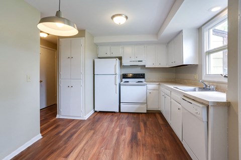 A kitchen with white appliances and wooden floors.