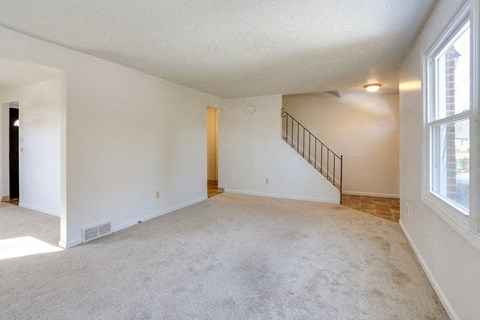A spacious room with a staircase and a window.