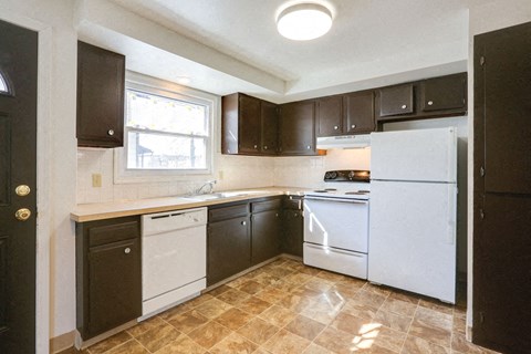 A kitchen with brown cabinets and a white refrigerator.