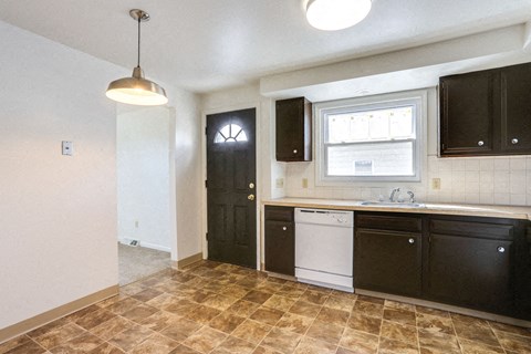 A kitchen with black cabinets and a tiled floor.