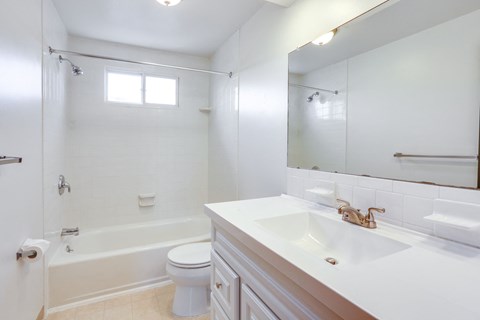 A white bathroom with a toilet, sink, and bathtub.