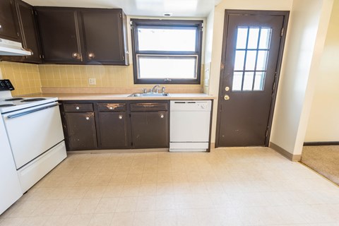 A kitchen with white appliances and brown cabinets.