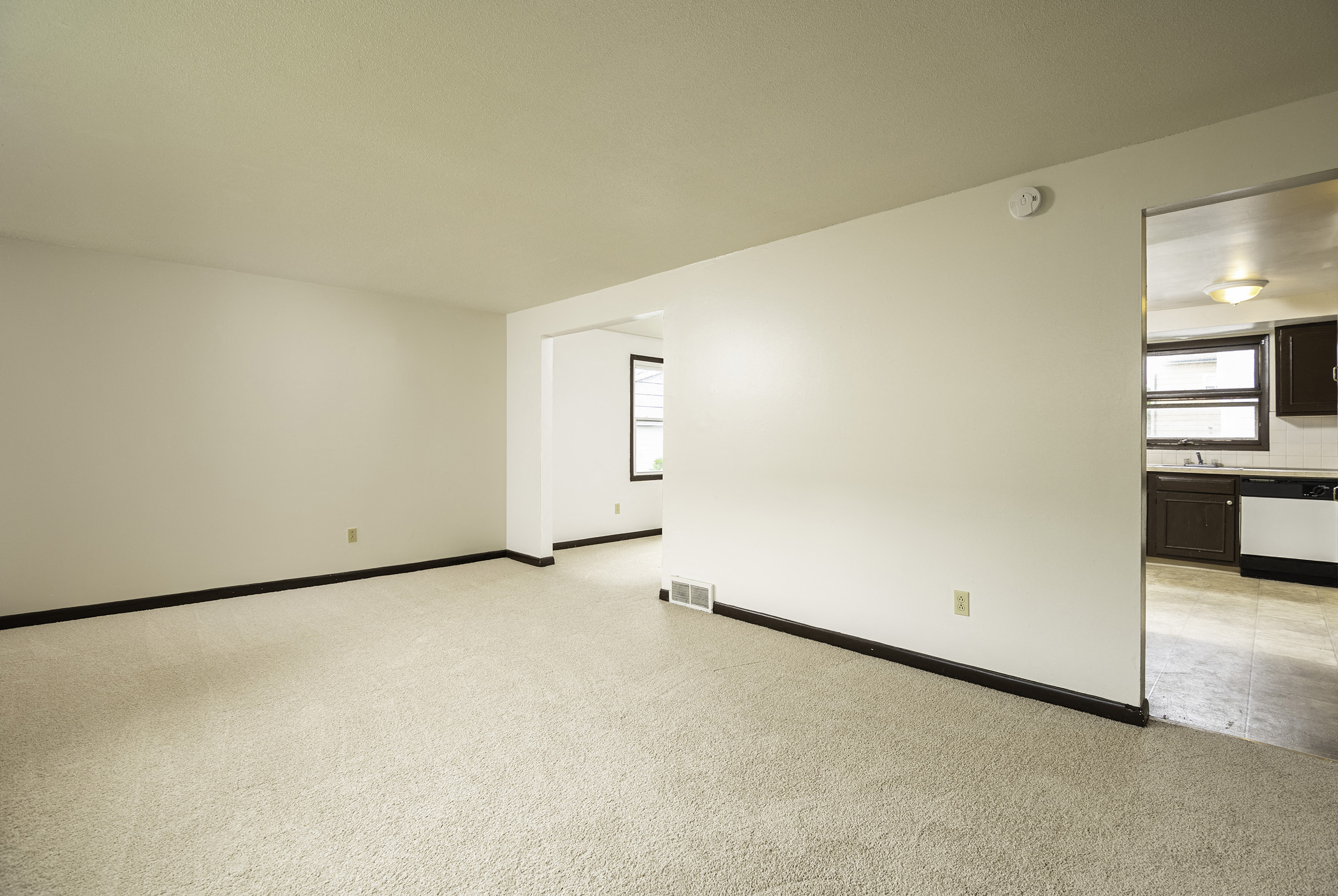 the living room and kitchen of an empty house with white walls