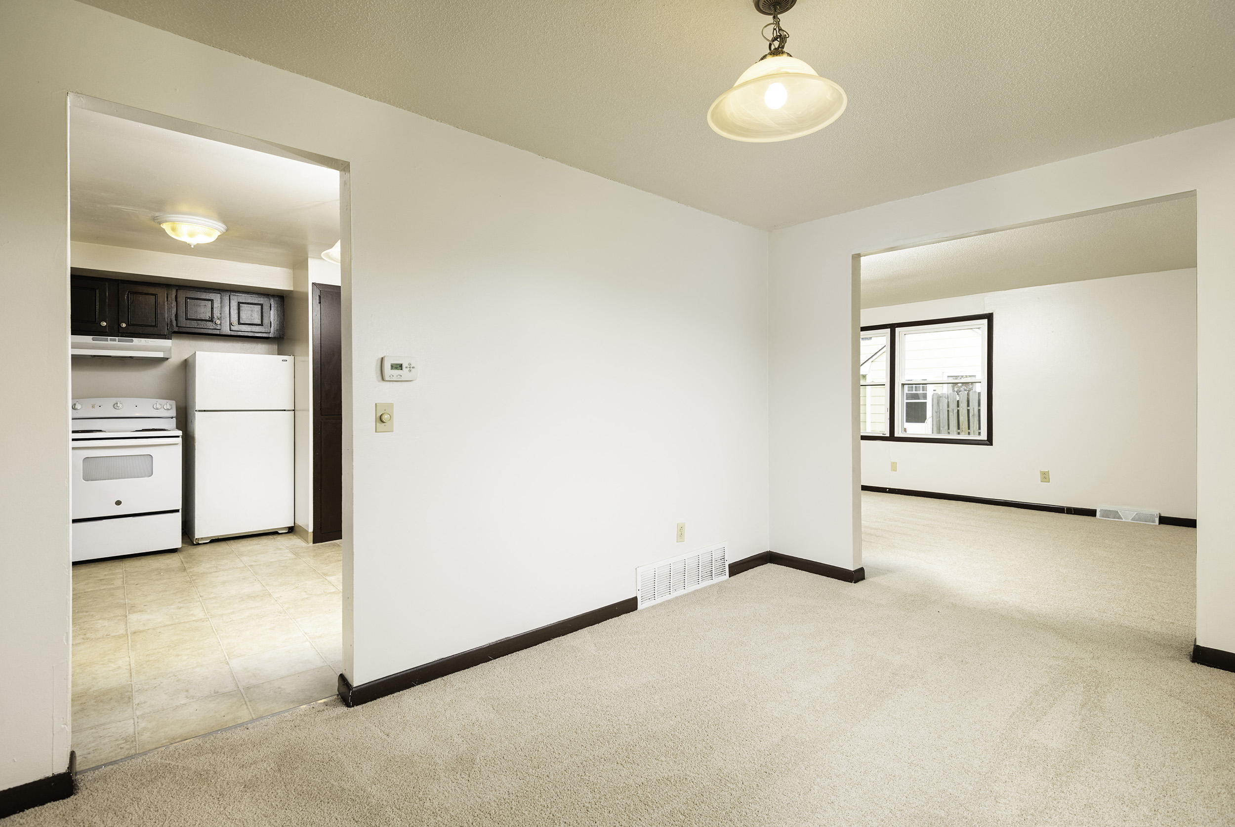 the living room and kitchen of an empty apartment with white walls and tile flooring
