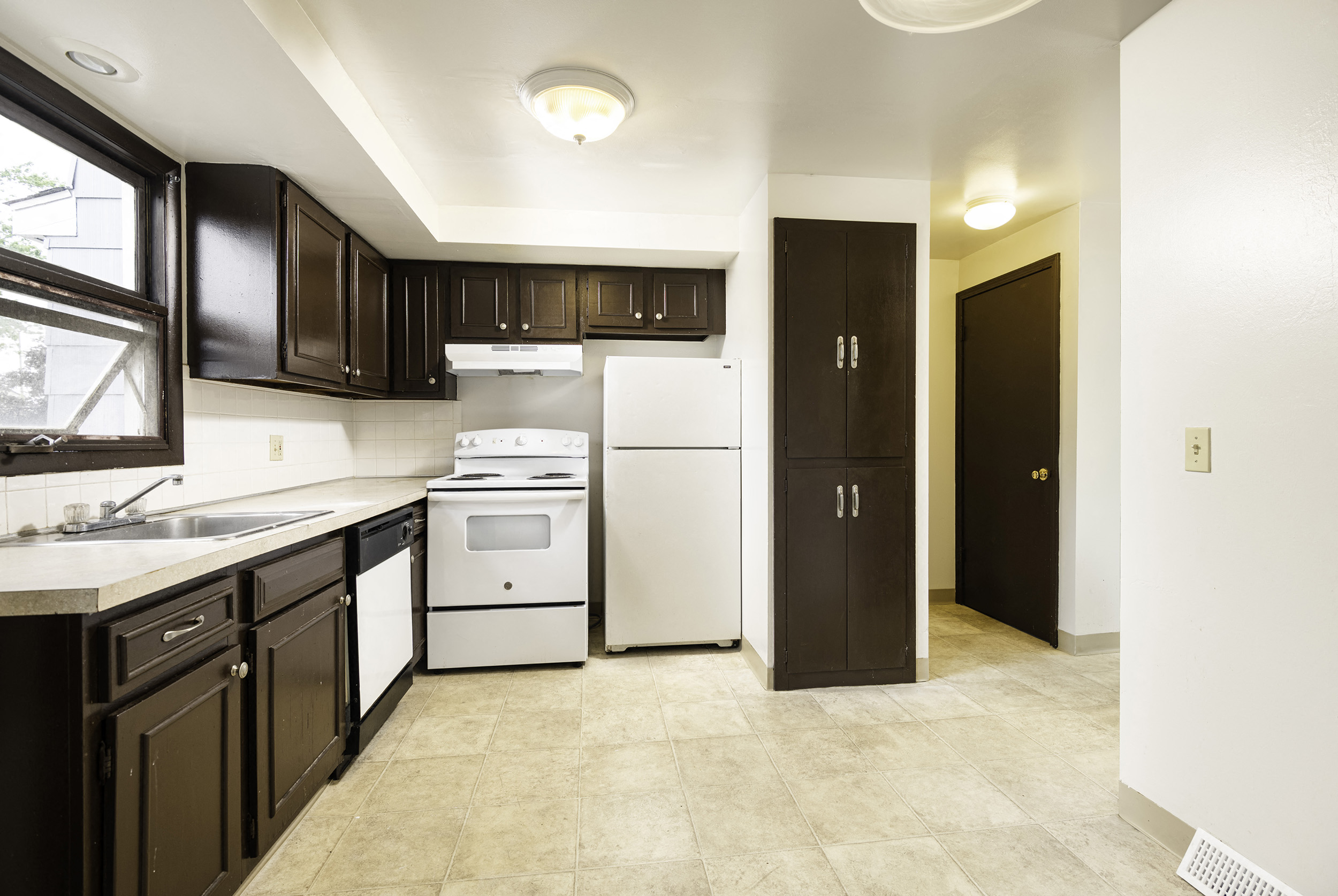 a kitchen with white appliances and black cabinets and a window