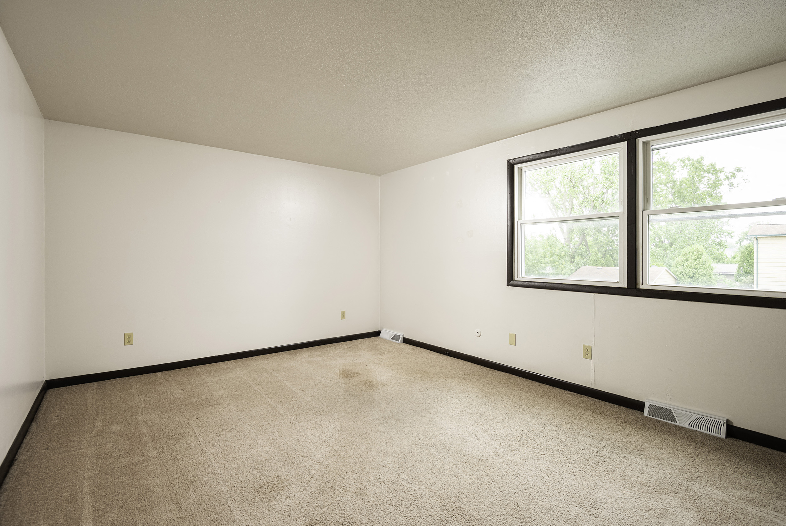 room with large windows and carpeting in an empty room