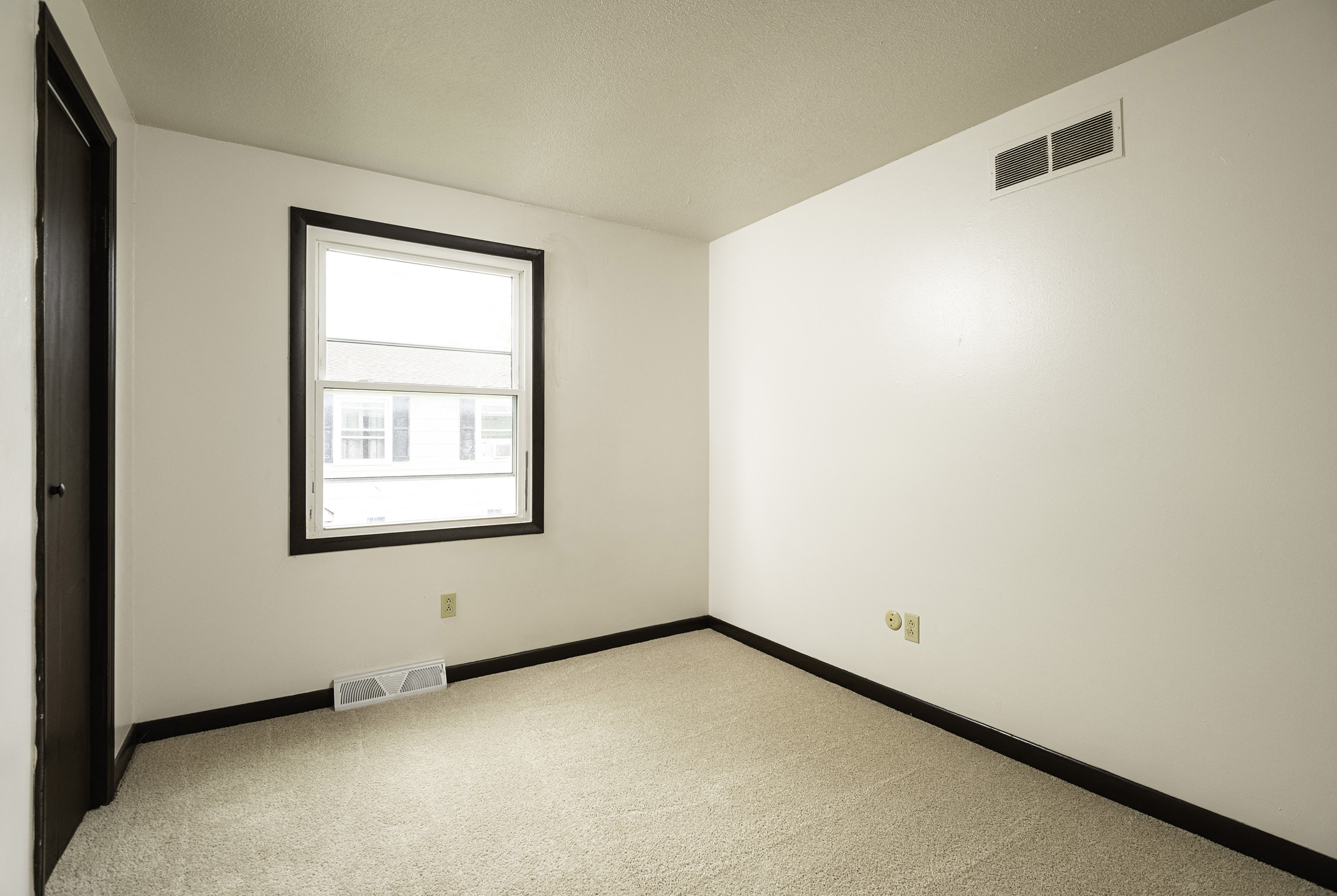 an empty room with a window and white walls