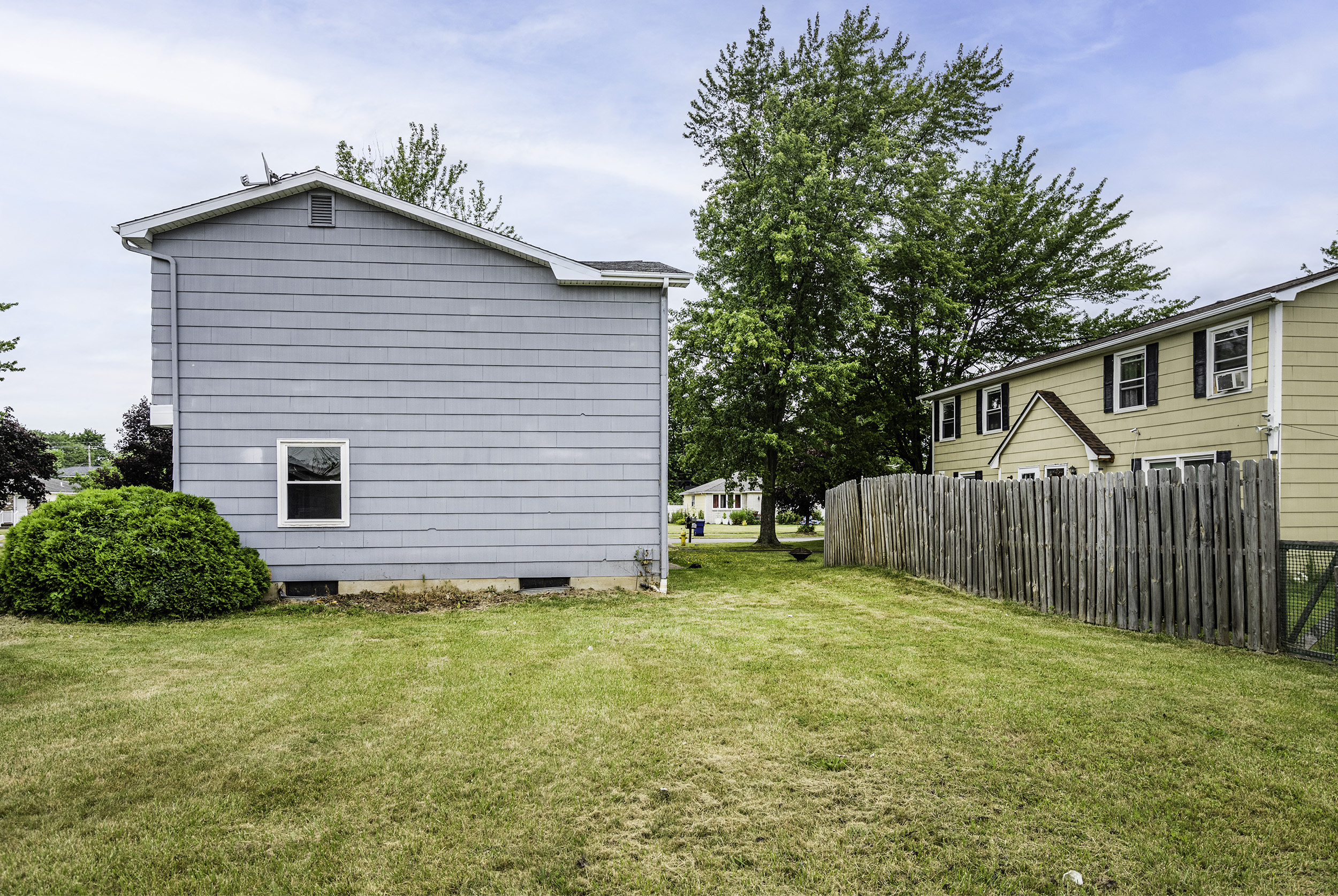 a backyard with a white house and a wooden fence