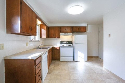 A kitchen with white appliances and brown cabinets.