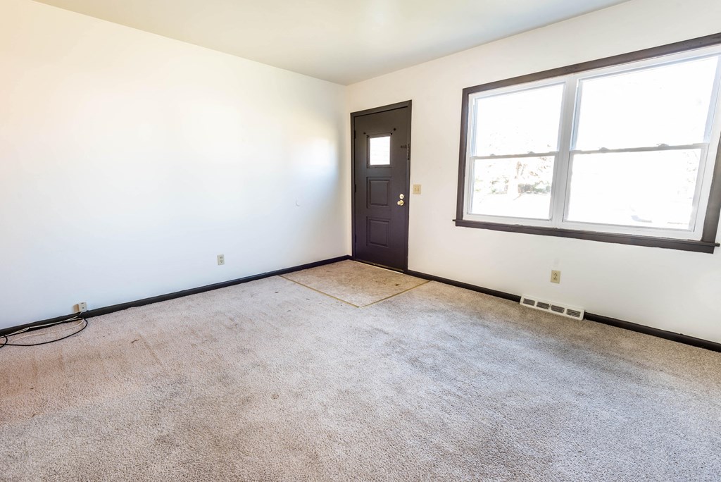 an empty room with a door and two windows