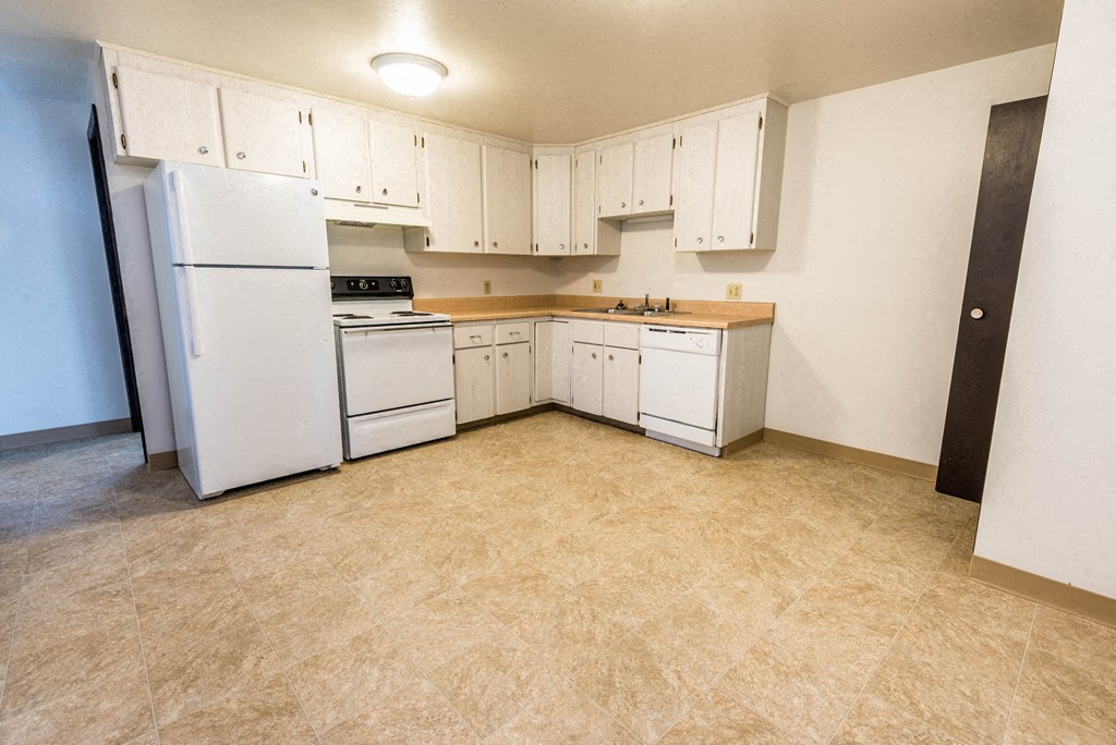 an empty kitchen with white appliances and white cabinets