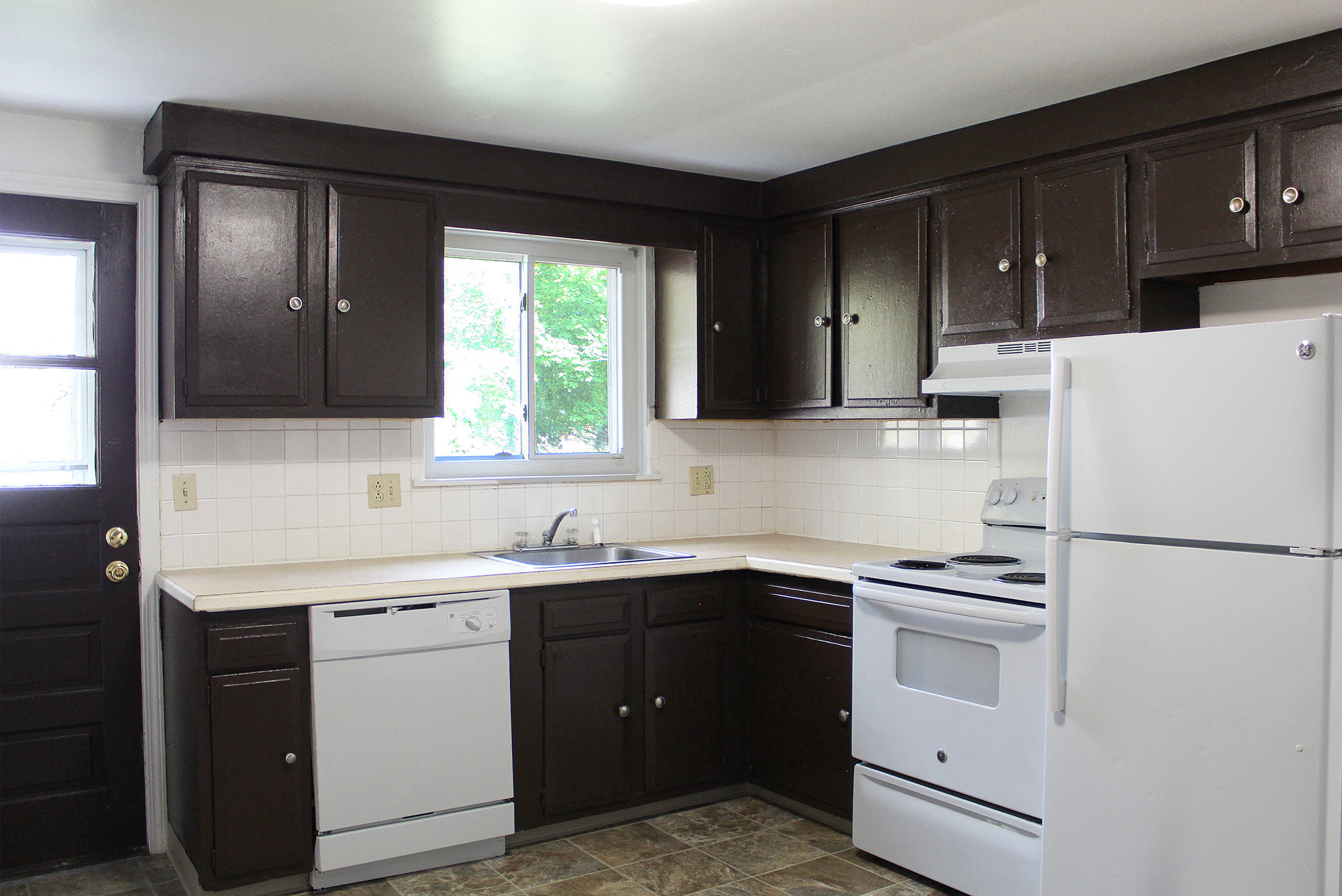 A kitchen with white appliances and brown cabinets.
