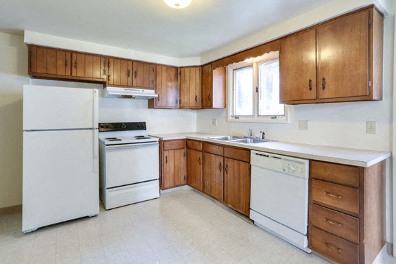 A kitchen with white appliances and wooden cabinets.