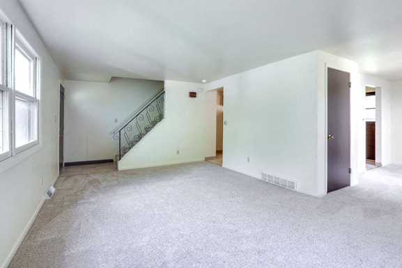 A spacious empty room with a staircase and a door.