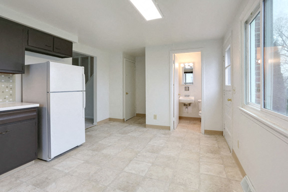 A kitchen with a white refrigerator and a tiled floor.