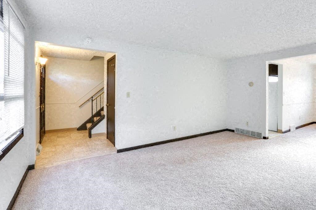 an empty living room with white walls and a staircase