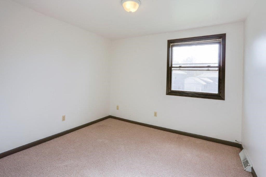 an empty room with a window and a carpet