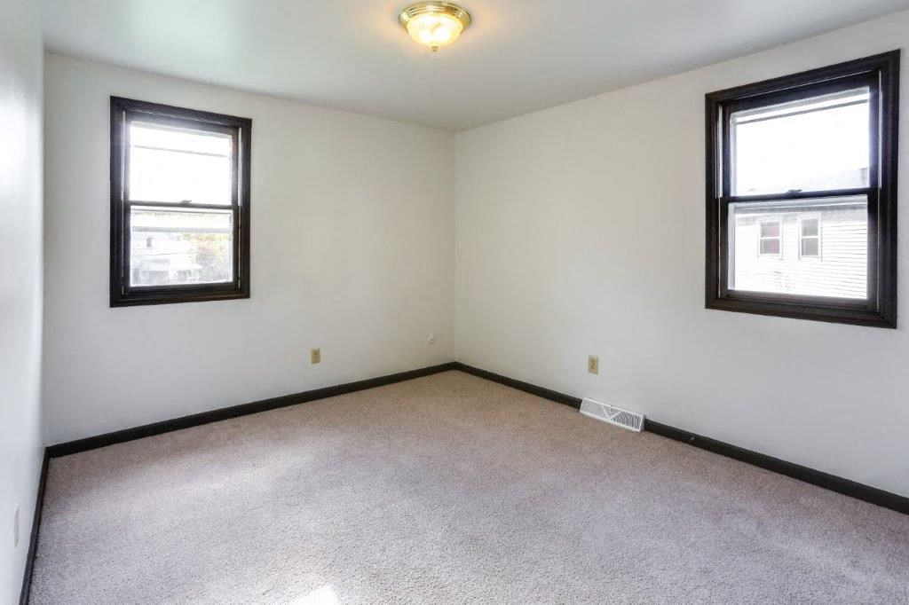 an empty living room with two windows and a carpet