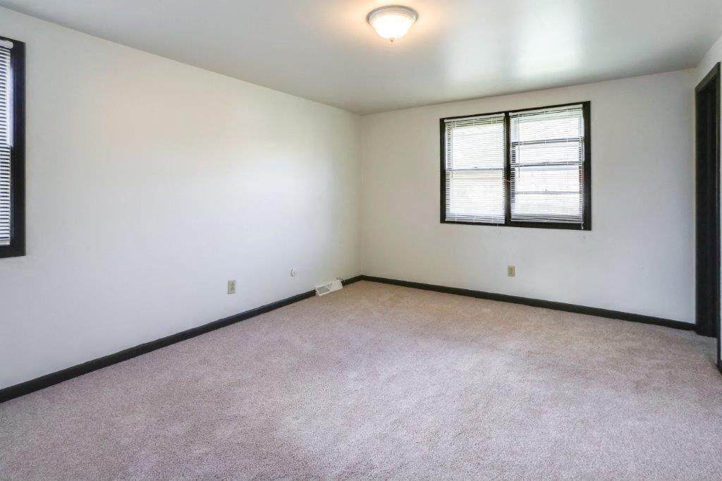 an empty living room with white walls and a window