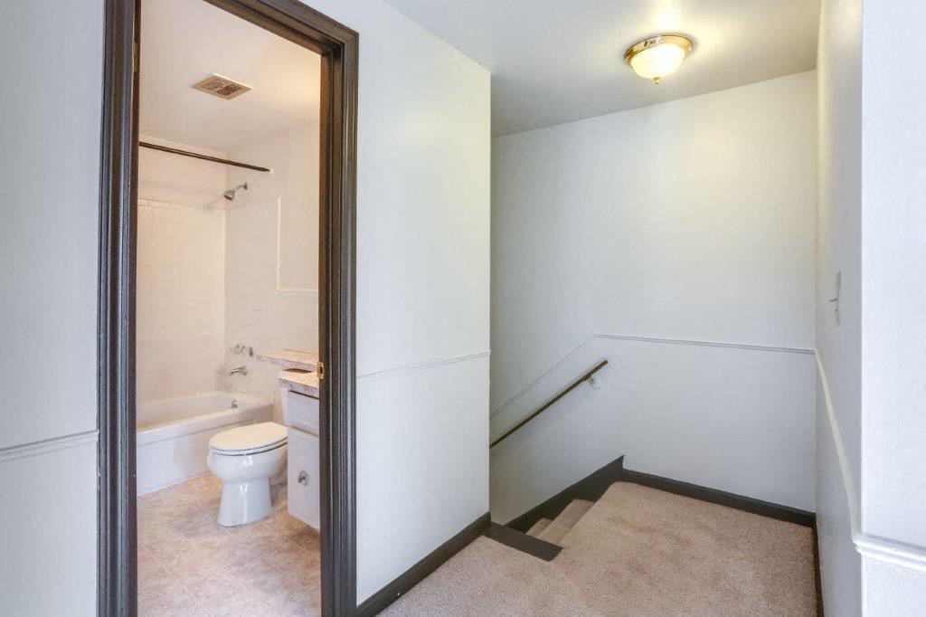 a white bathroom with a toilet and a staircase