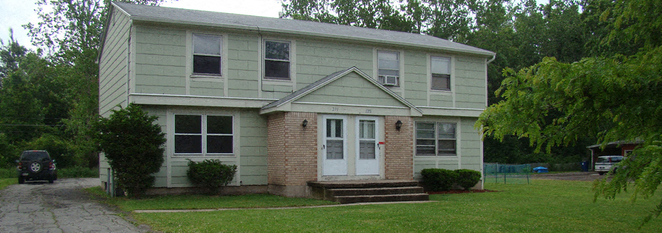 a white house with a white door and a green and brick porch