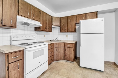 A kitchen with white appliances and wooden cabinets.