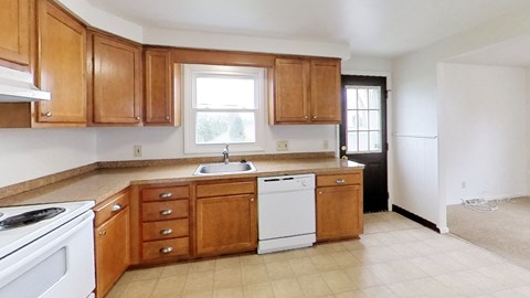 A kitchen with wooden cabinets and a white dishwasher.
