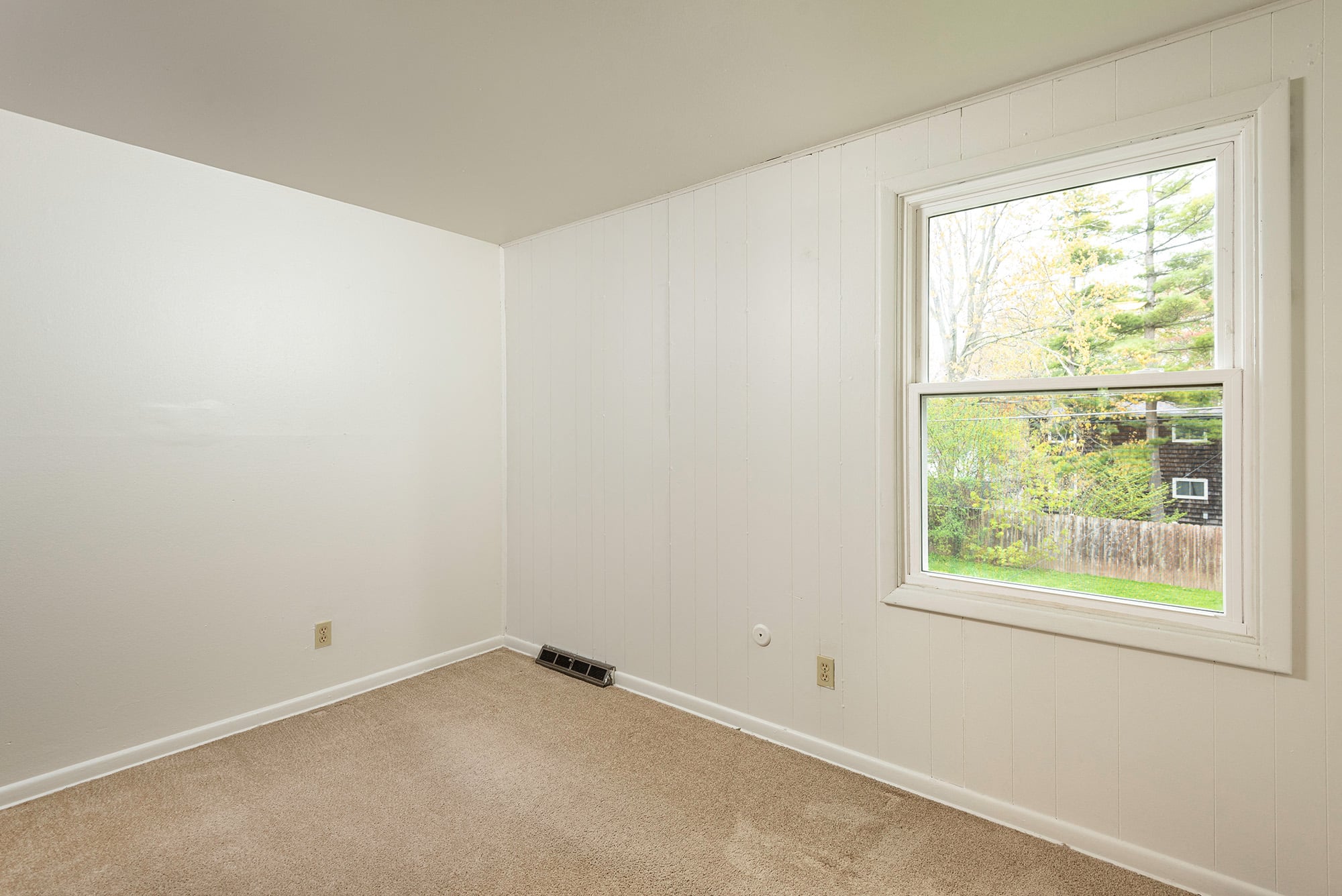 a bedroom with a large window and white walls