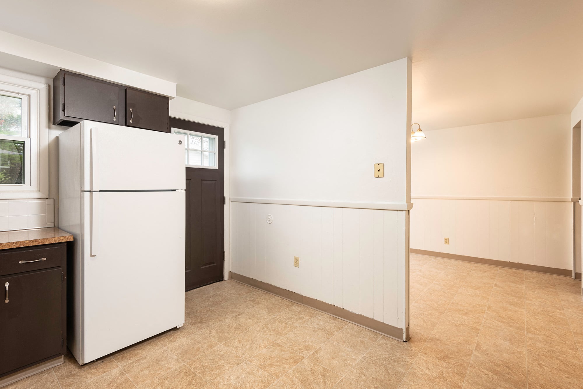 a kitchen with a white refrigerator and a black door