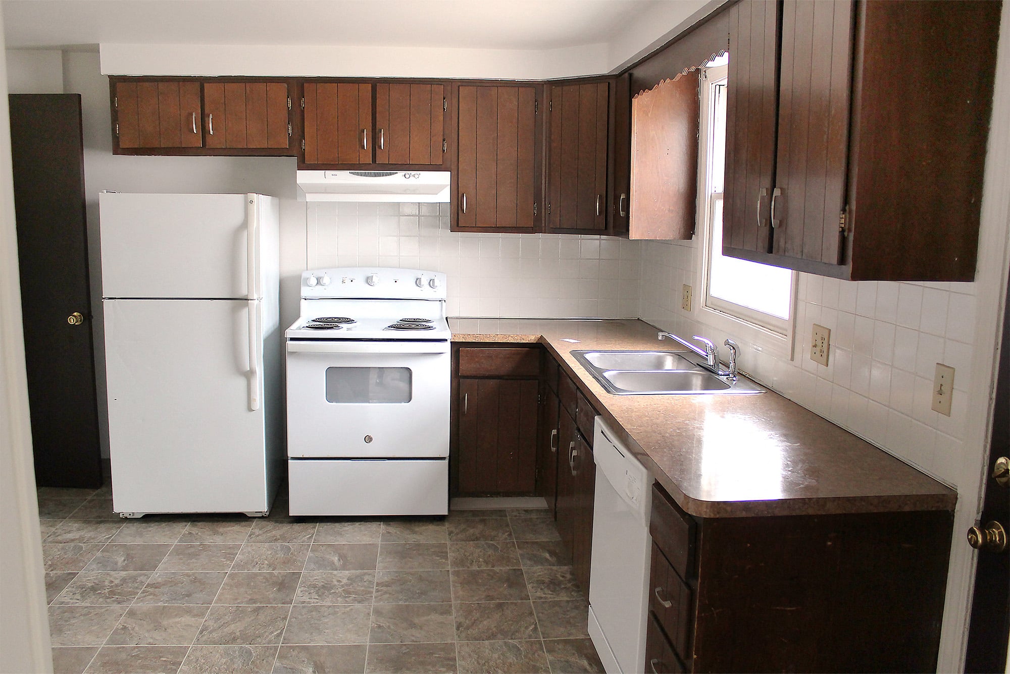 an empty kitchen with white appliances and wooden cabinets