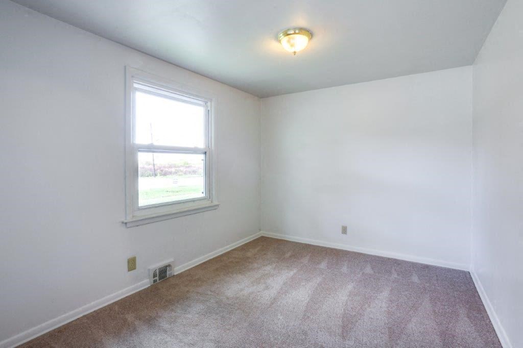 an empty living room with a window and carpet