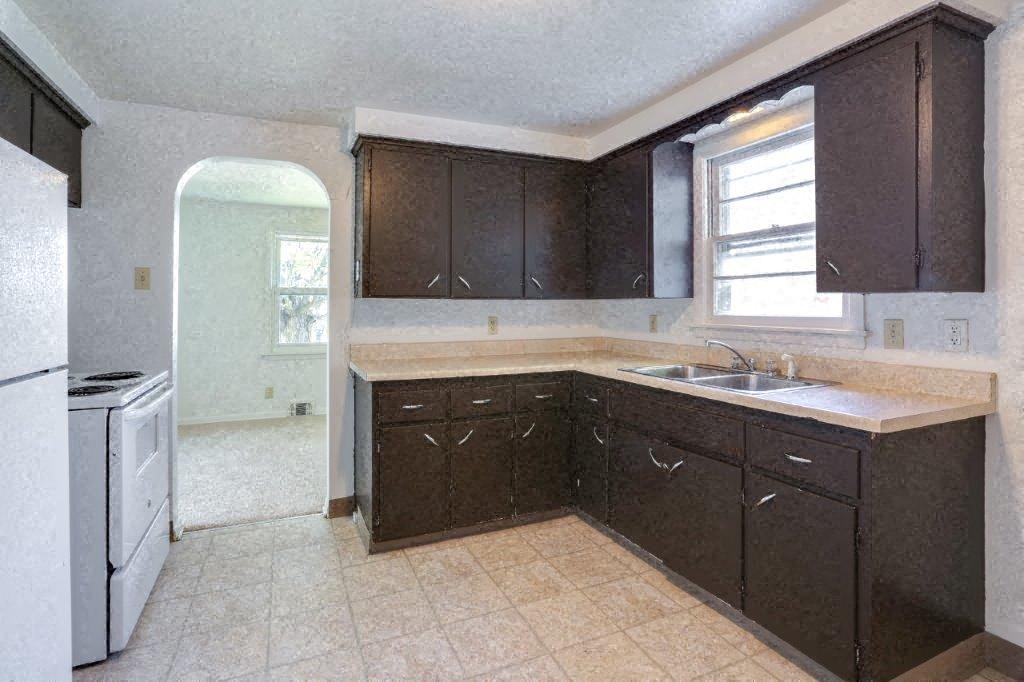 an empty kitchen with a sink and a refrigerator