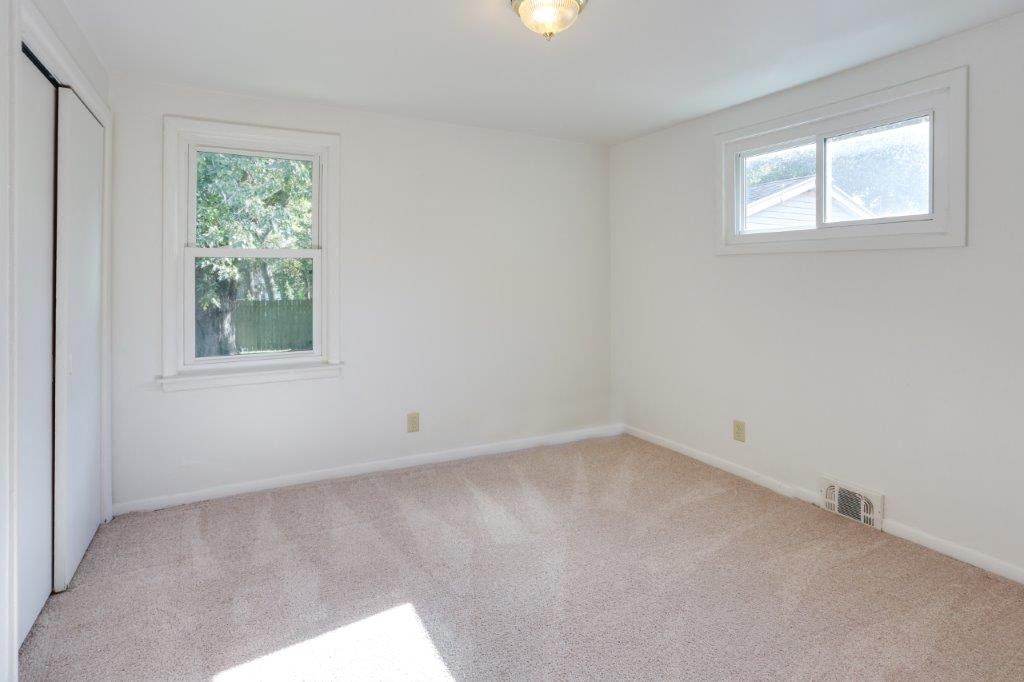 an empty living room with two windows and a carpet