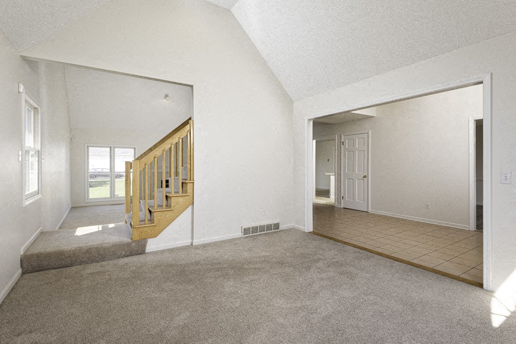 A room with a staircase and a doorway leading to another room.