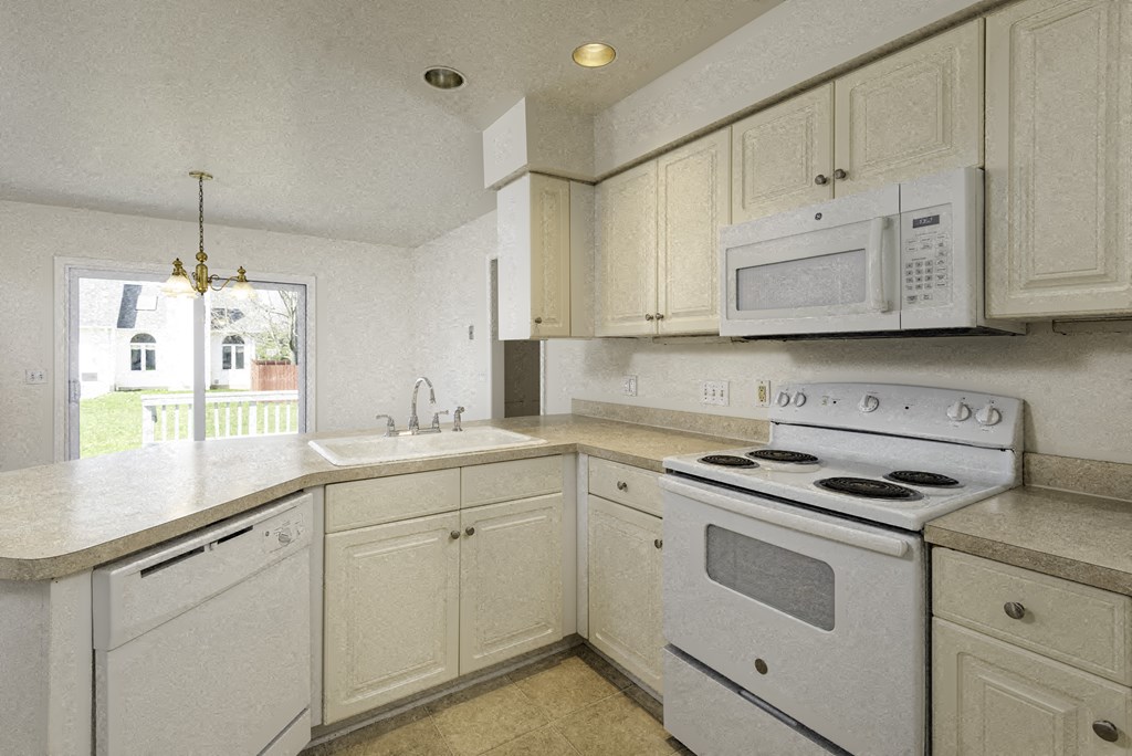 A white kitchen with a stove, sink, and cabinets.