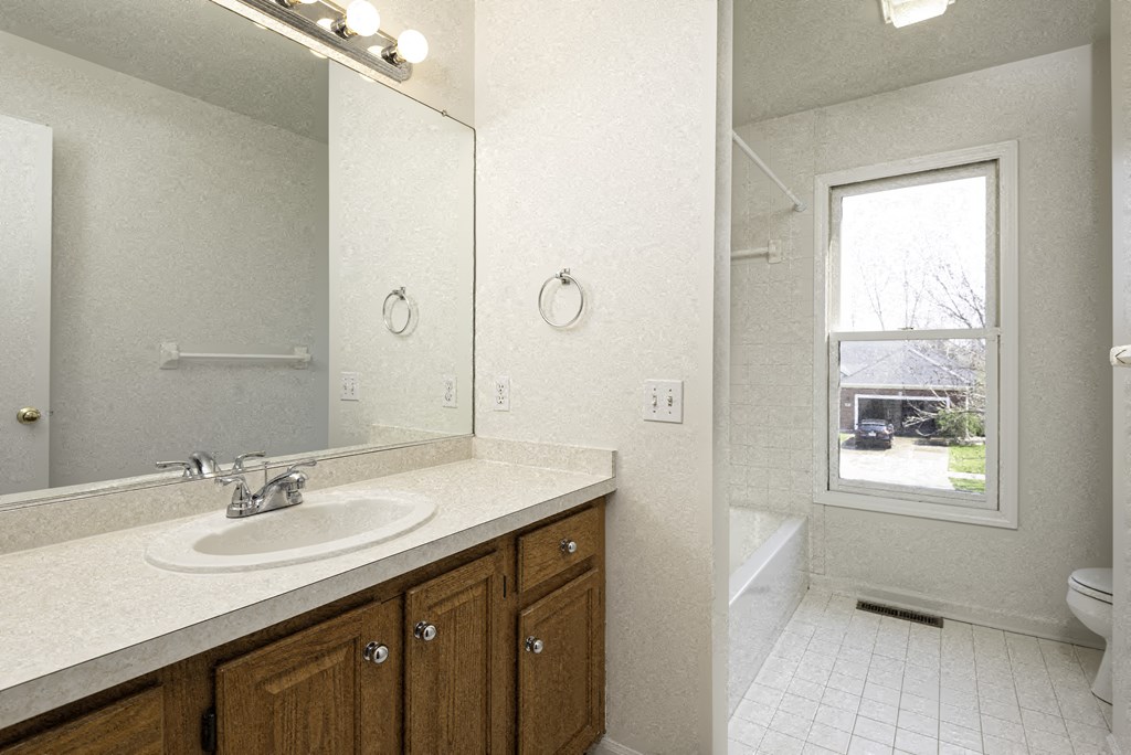 A bathroom with a sink, mirror, and a window.