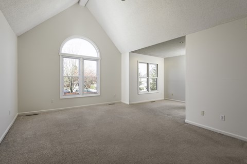 A spacious room with a large window and carpeted floor.