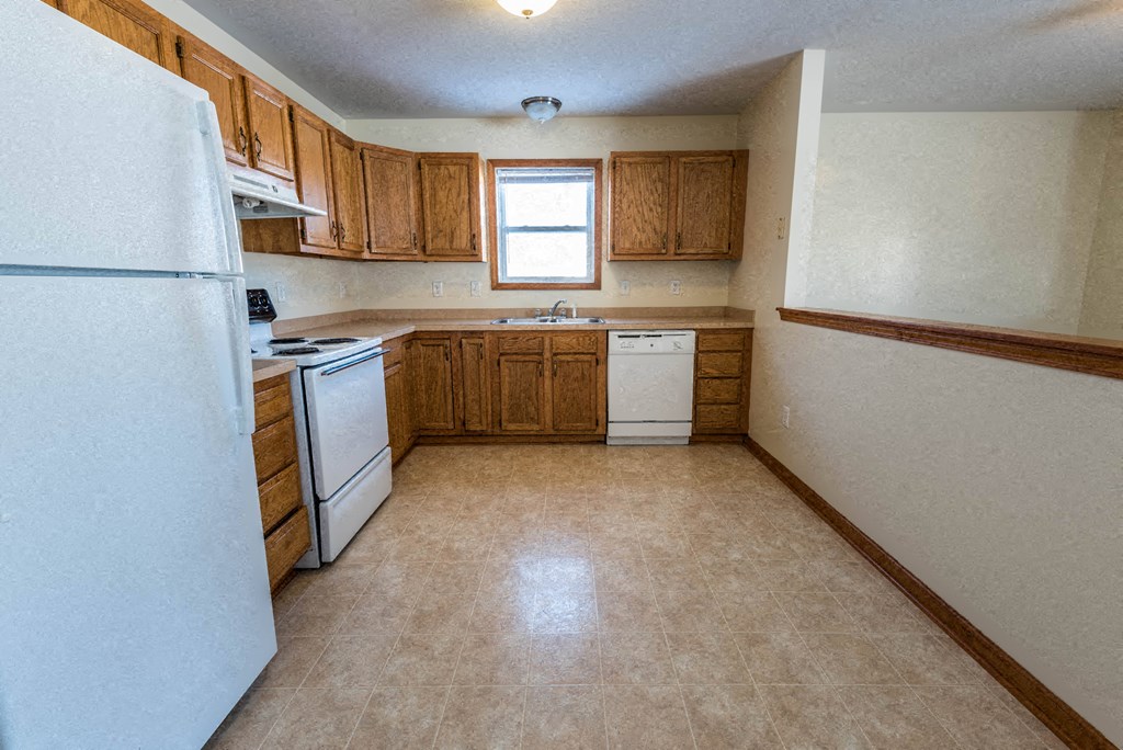an empty kitchen with white appliances and wooden cabinets
