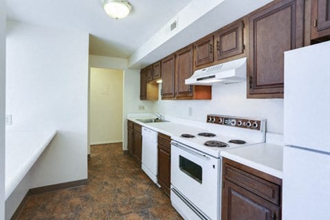 an empty kitchen with white appliances and wooden cabinets
