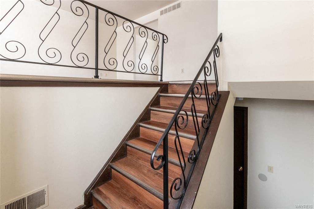 stairs in a home with a railing and a white wall