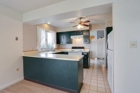 A kitchen with a black counter and a fan.
