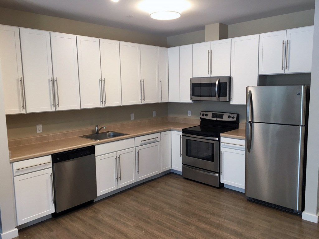 an empty kitchen with white cabinets and stainless steel appliances