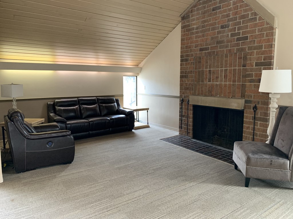a living room with leather furniture and a brick fireplace
