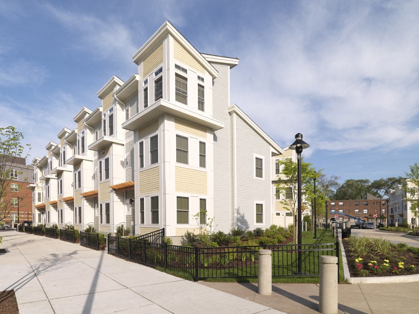 a row of town homes with white siding and a sidewalk