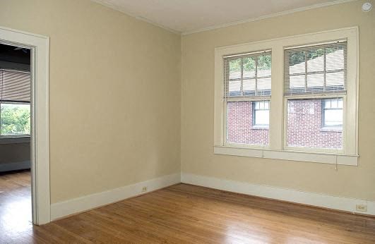 an empty room with two windows and a wooden floor