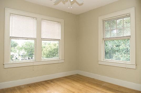 an empty room with two windows and a wooden floor