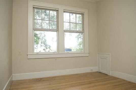 a empty room with two windows and a wooden floor